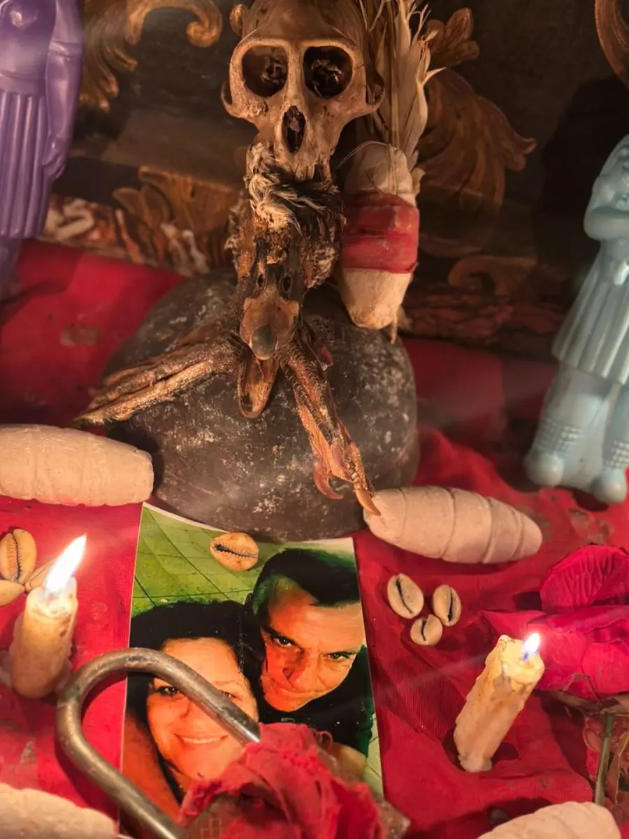 Manos entrelazadas junto a velas de amarre de amor y pétalos de rosa